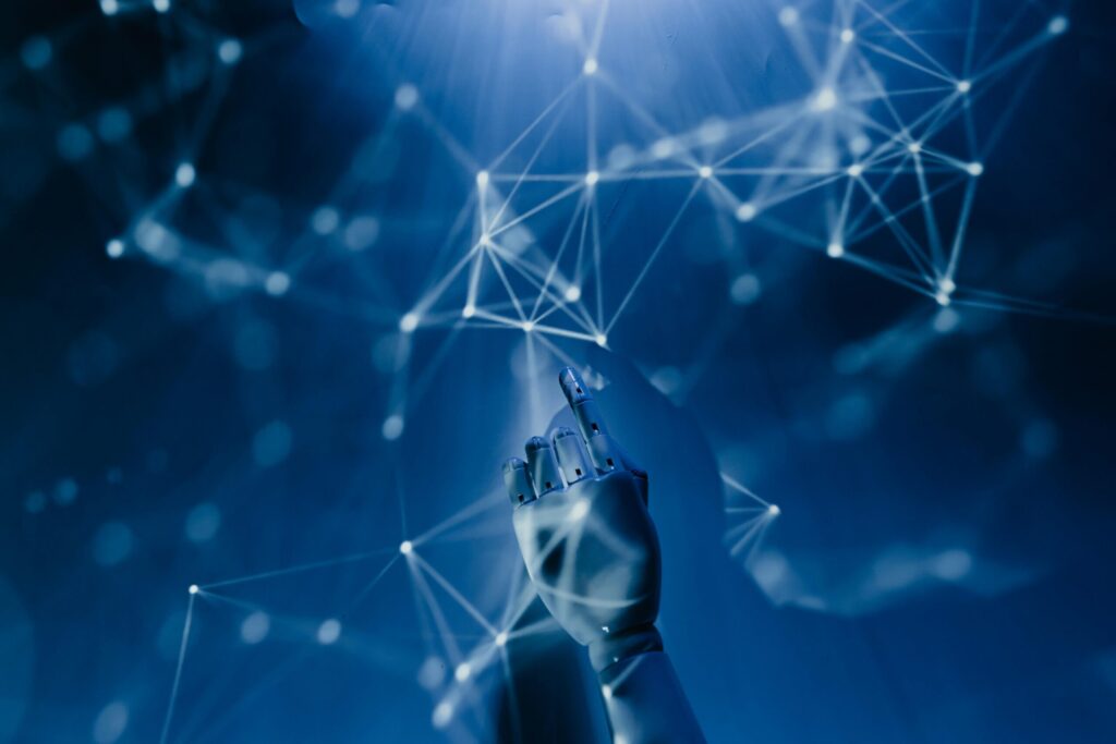 Free A robotic hand reaching into a digital network on a blue background, symbolizing AI technology. Stock Photo