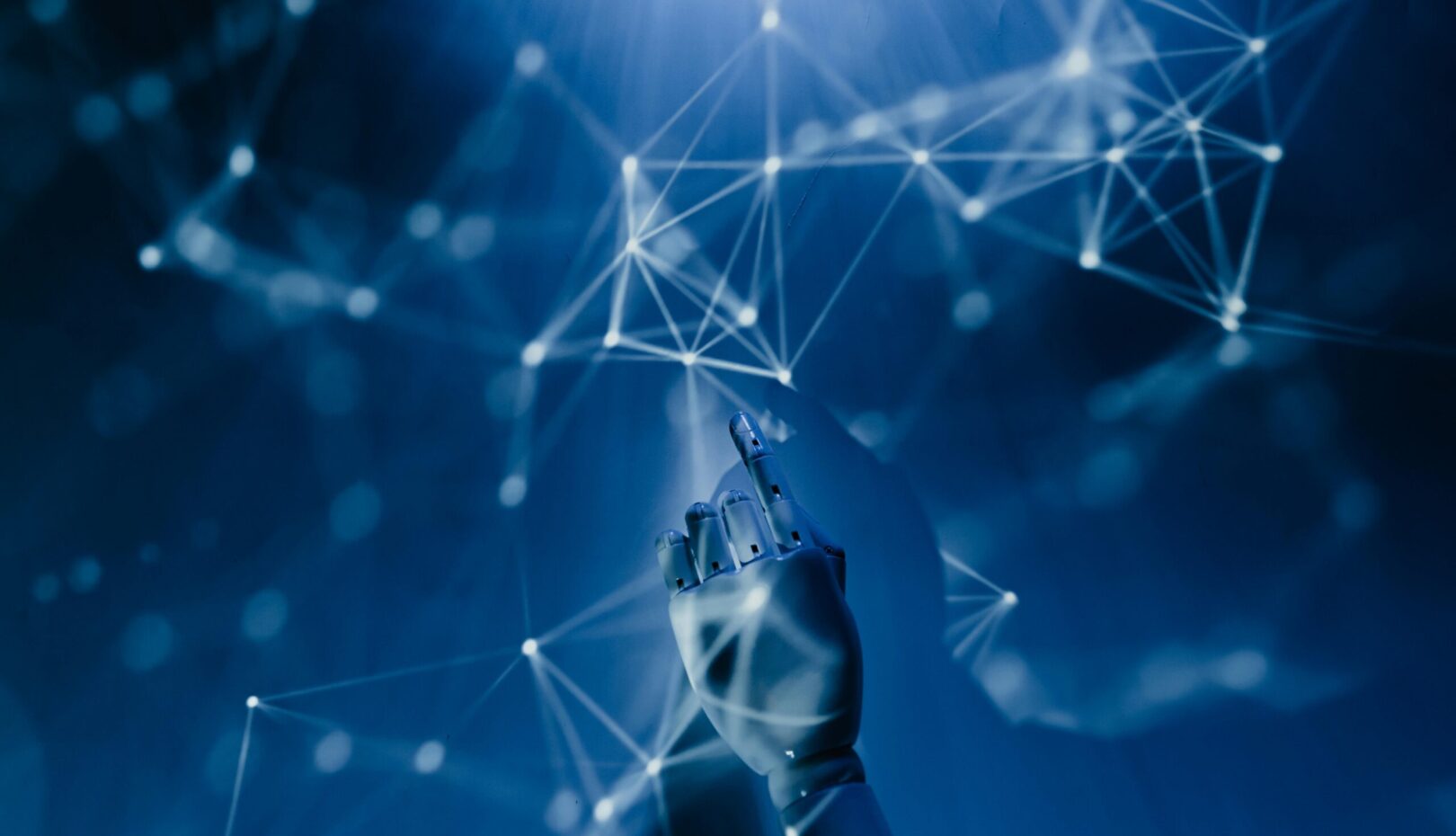 Free A robotic hand reaching into a digital network on a blue background, symbolizing AI technology. Stock Photo